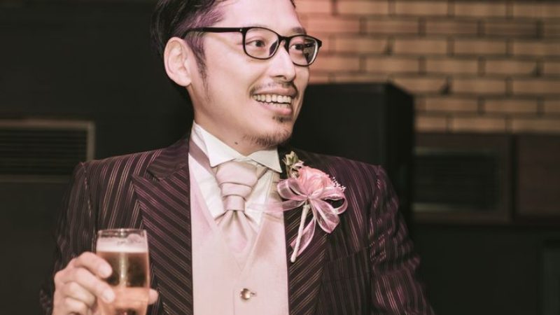 スーツ姿でグラスを持ち会場を見ている男性