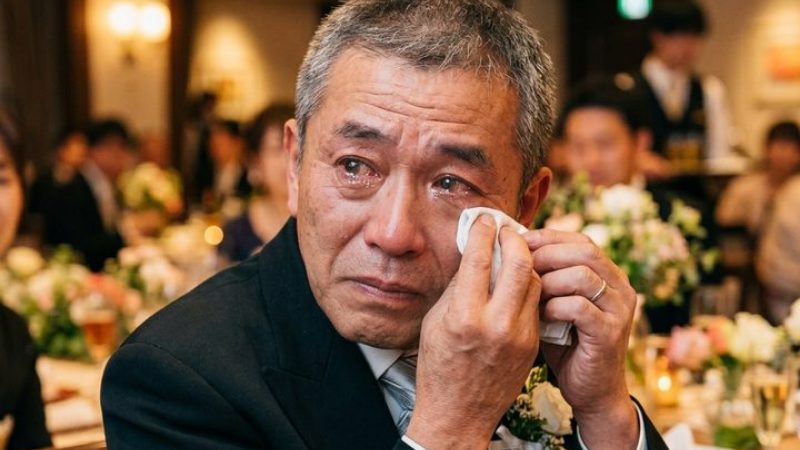 披露宴の席で目もとをハンカチでぬぐう年配の男性