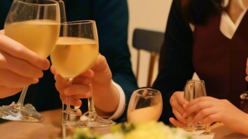 テーブルでグラスを合わせて乾杯する人たちの手もと