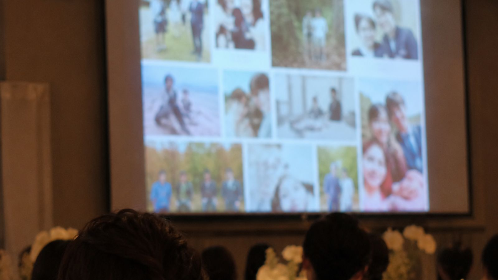 披露宴会場の大きなスクリーンに、ゲストが撮った写真が並んで映し出され、席から見上げている様子